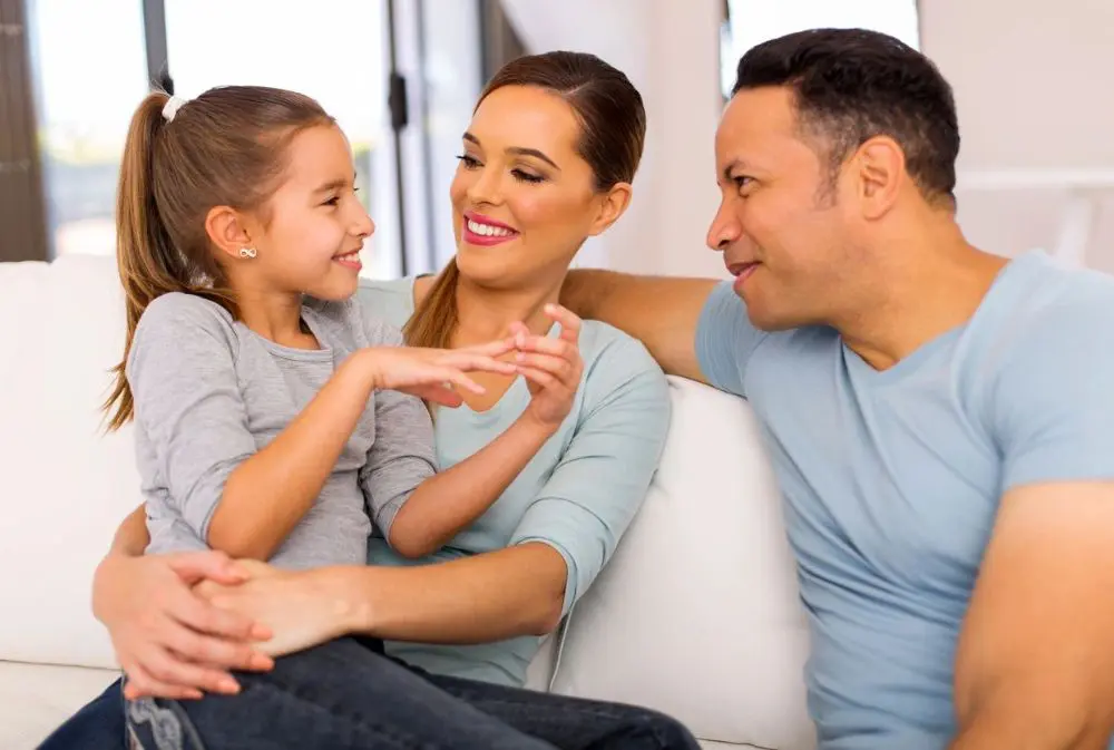 A woman and two men sitting on top of a couch.