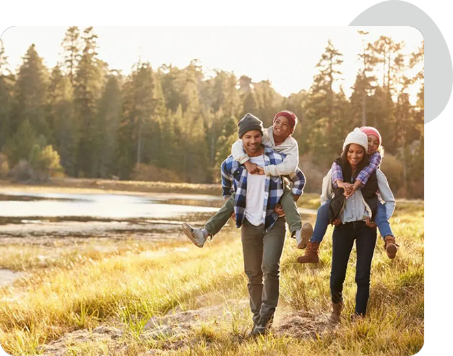 A group of people walking in the grass near water.